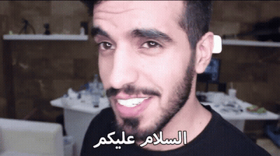 Bearded Man Smiling In Front Of Arabic Writing GIF