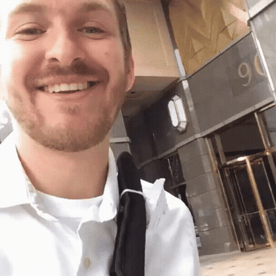 Bearded Man Smiling In Front Of Building Number 90 GIF