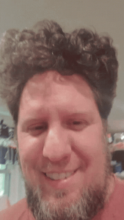 Bearded Man Smiling In Front Of Cat Curtain GIF