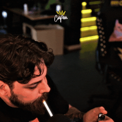 Bearded Man Smoking In Front Of Capon Sign GIF