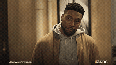 Bearded Man Standing In Front Of New Amsterdam Sign GIF