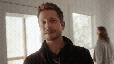 Bearded Man Standing With Woman In Background GIF
