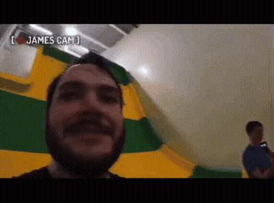 Bearded Man Taking Selfie In Front Of Yellow And Green Flag GIF