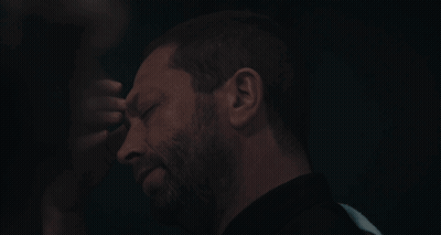 Bearded Man Touching Forehead In Dark Room GIF