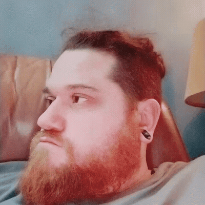 Bearded Man With Ear Plugs Laying On Couch GIF