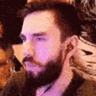 Bearded Man With Earbuds Sitting At Table GIF