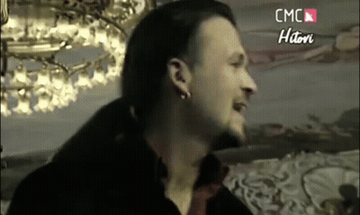 Bearded Man With Earrings Smiling In Front Of Chandelier GIF