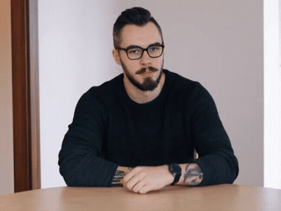 Bearded Man With Glasses Arms Crossed At Table GIF