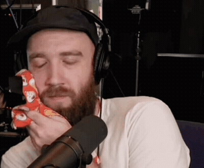 Bearded Man With Headphones And Hat Holding Napkin To Face GIF