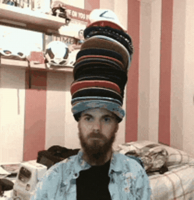 Bearded Man With Stack Of Hats GIF