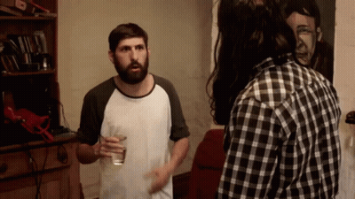 Bearded Man With Water Glass Talks To Plaid Shirt Man GIF