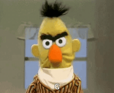 Bert From Sesame Street Is Angry And Says `` G '' While Standing In Front Of A Window . GIF