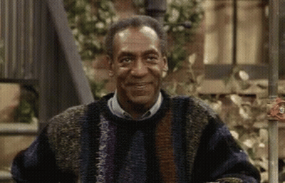 Bill Cosby Is Wearing A Sweater And Smiling While Sitting On A Bench . GIF