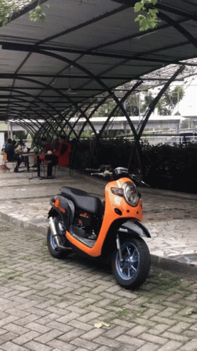 Black And Orange Scooter Parked Under Covered Walkway GIF