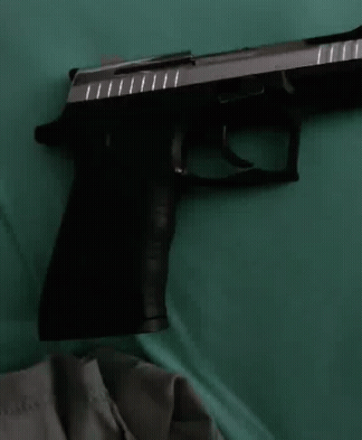 Black And Silver Gun On Green Cloth GIF