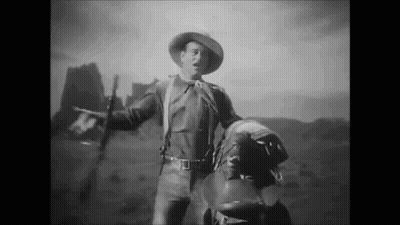 Black And White Cowboy Holding Saddle And Gun GIF