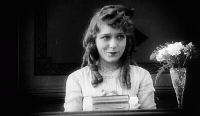 Black And White Girl With Book And Vase Of Flowers GIF