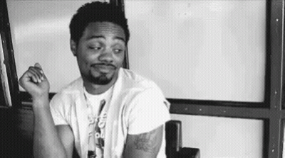 Black And White Man Sitting In Chair With Hands In Pockets GIF
