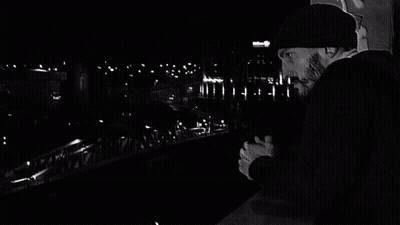 Black And White Man Walking Across Bridge With Graffiti GIF