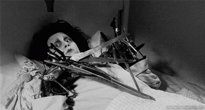 Black And White Person In Bed With Scissors GIF