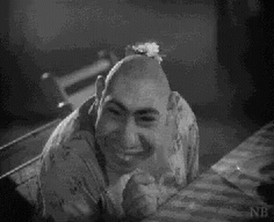 Black And White Photo Of Bald Man Sitting On Bed GIF