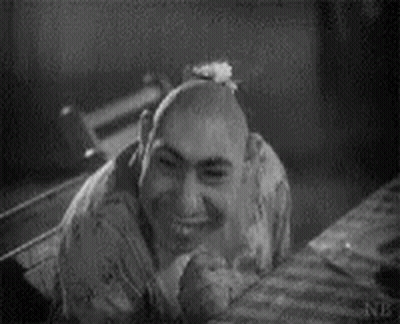 Black And White Photo Of Bald Man Smiling On Bed GIF