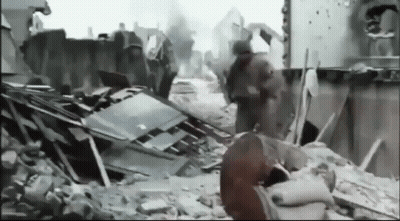 Black And White Photo Of Destroyed City With Soldiers Walking Through Rubble GIF