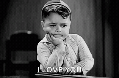 Black And White Photo Of Little Boy With Hand On Chin At Desk GIF