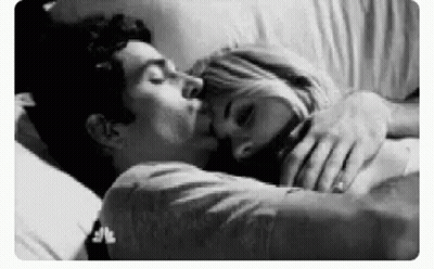 Black And White Photo Of Man And Woman Kissing In Bed GIF