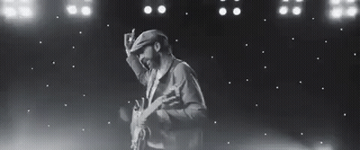 Black And White Photo Of Man Holding Guitar On Stage GIF