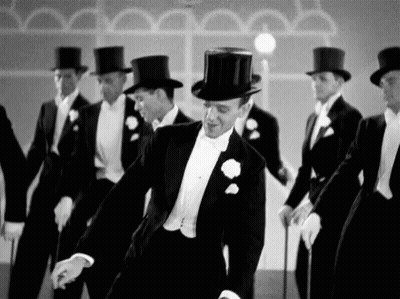 Black And White Photo Of Men In Tuxedos And Top Hats Dancing GIF