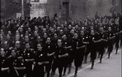 Black And White Photo Of Men Marching Down Street GIF