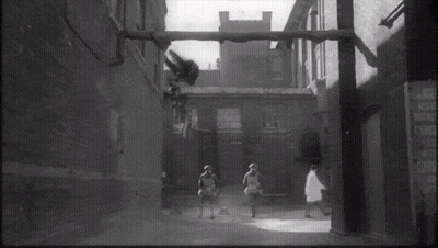 Black And White Photo Of People Walking Down Street With Sign GIF