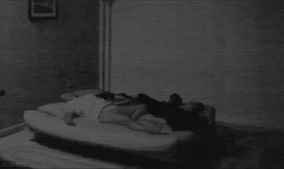 Black And White Photo Of Person Laying On Bed In Dark Room GIF