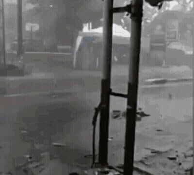 Black And White Photo Of Person Standing Next To Pole In Street GIF