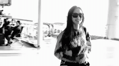 Black And White Photo Of Woman In Sunglasses At Airport GIF
