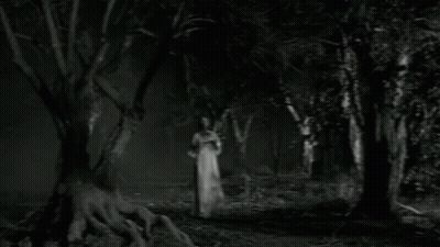 Black And White Photo Of Woman In White Dress In Dark Forest GIF