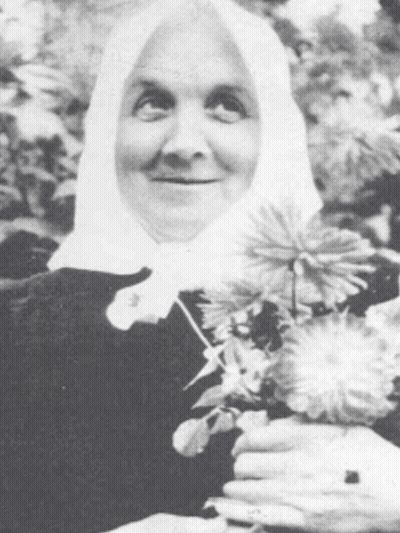 Black And White Photo Of Woman In White Head Scarf Holding Flowers GIF