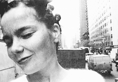 Black And White Photo Of Woman Standing In Front Of Building GIF