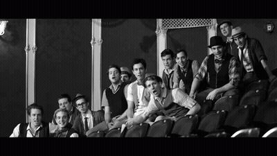 Black And White Photo Of Young Men Sitting In Theater GIF