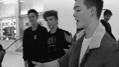 Black And White Photo Of Young Men Standing In Mall GIF