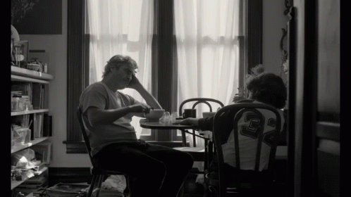 Black And White Photo Two People At Table Man Wearing Number 29 Shirt GIF