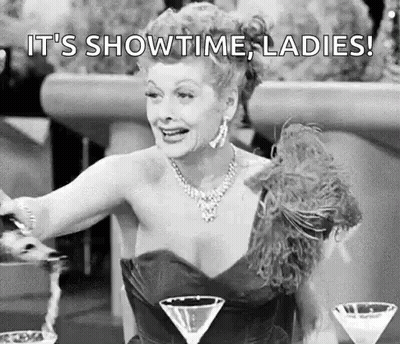 Black And White Woman In Dress Sitting At Table With Martinis GIF