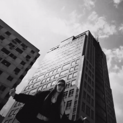 Black And White Woman In Front Of Tall Building GIF