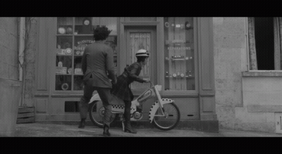 Black And White Woman Riding Motorcycle In Front Of Bijoutier Store GIF