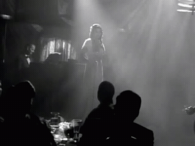 Black And White Woman Singing Into Microphone In Front Of Crowd GIF