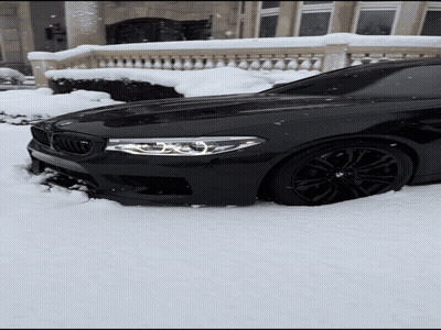 Black BMW Stuck In Snow In Front Of Building GIF