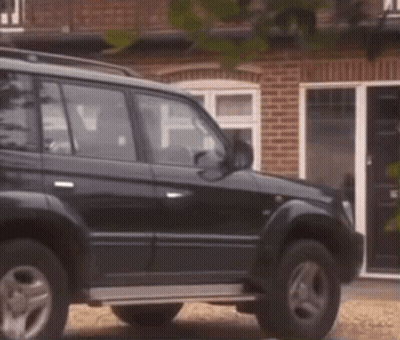 Black Car Parked In Front Of Brick House GIF