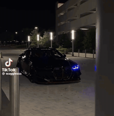 Black Car Parked Next To Tik Tok Sign GIF
