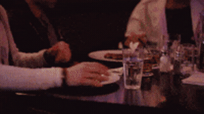 Black Cat Sitting On Wooden Floor Looking Up GIF